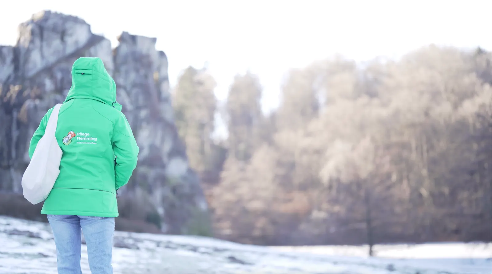 Pflegekraft von Pflege Flemming in grüner Jacke vor den Externsteinen