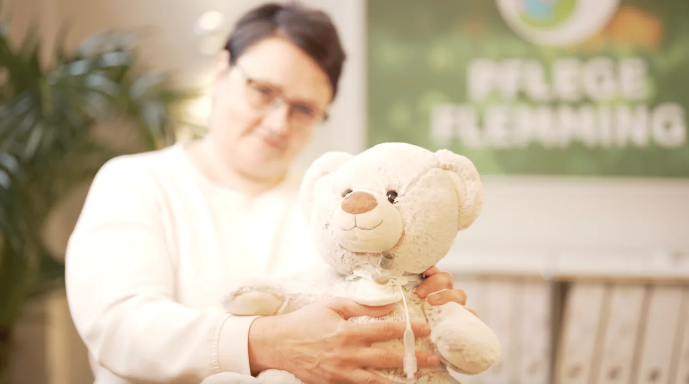 Pflegekraft mit Teddy zur Demonstration der Kinderintensivpflege